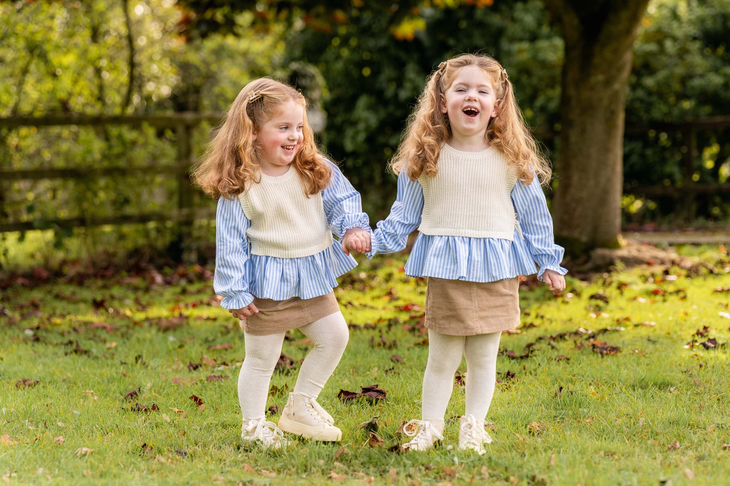 Twin sisters laughing having their photo taken.